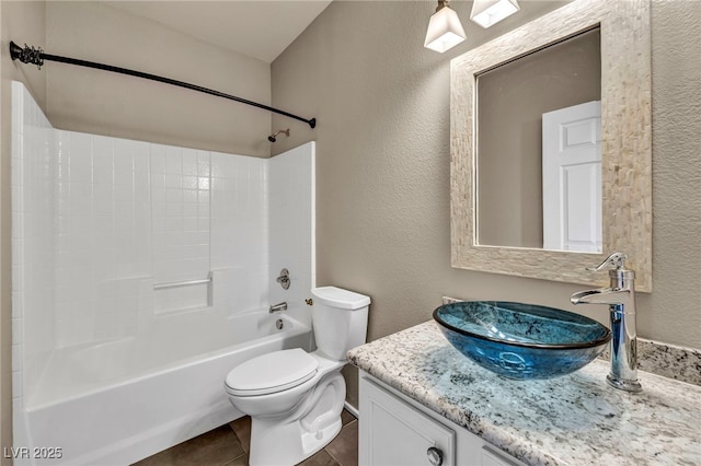 bathroom with a textured wall, tile patterned flooring, toilet, vanity, and washtub / shower combination