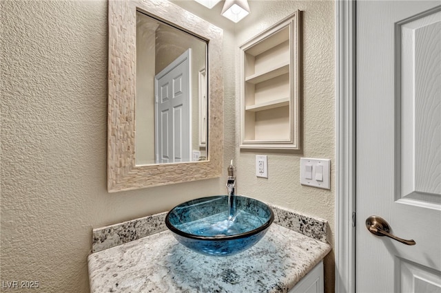 bathroom featuring vanity and a textured wall