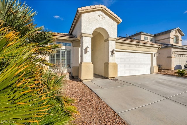 mediterranean / spanish-style home featuring an attached garage, driveway, a tile roof, and stucco siding