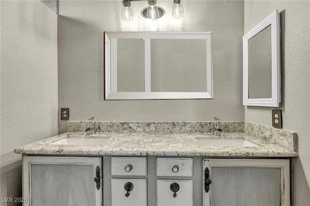 full bath featuring a textured wall, double vanity, and a sink