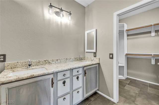 full bathroom featuring a spacious closet, a sink, and baseboards