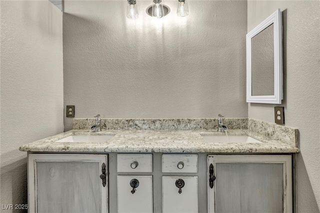 full bath with a textured wall, a sink, and double vanity