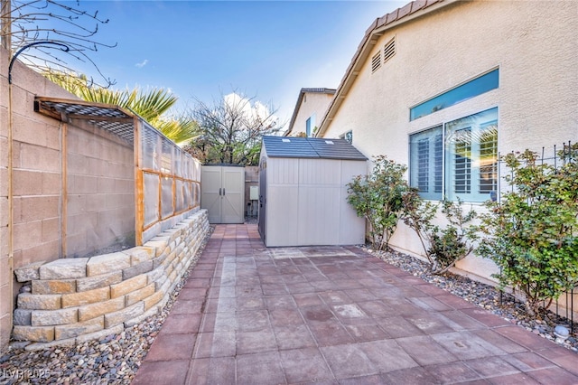 view of patio featuring a storage shed, an outbuilding, and a fenced backyard