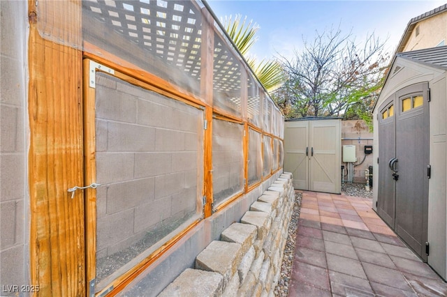 exterior space featuring an outbuilding, concrete block siding, fence, and a storage shed