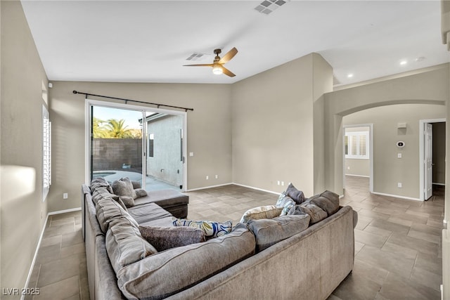 living room featuring visible vents, arched walkways, vaulted ceiling, and baseboards