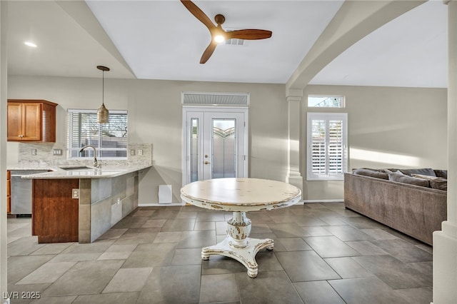 kitchen with backsplash, open floor plan, a sink, dishwasher, and a peninsula