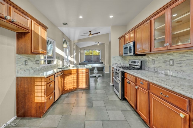 kitchen with ceiling fan, light stone counters, stainless steel appliances, open floor plan, and glass insert cabinets