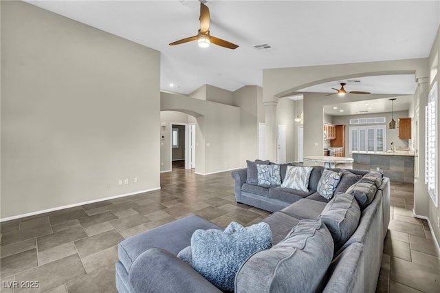 living area with arched walkways, lofted ceiling, visible vents, ceiling fan, and baseboards