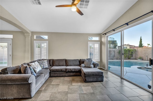 living room with lofted ceiling, a wealth of natural light, visible vents, and a ceiling fan