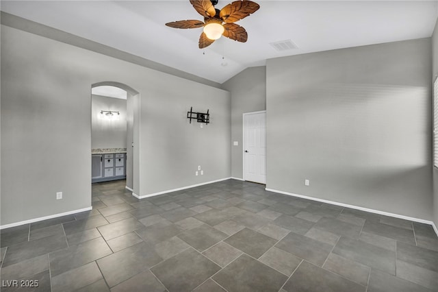 unfurnished room featuring arched walkways, ceiling fan, visible vents, baseboards, and vaulted ceiling