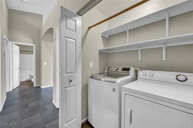 laundry room with laundry area, washing machine and dryer, baseboards, and arched walkways