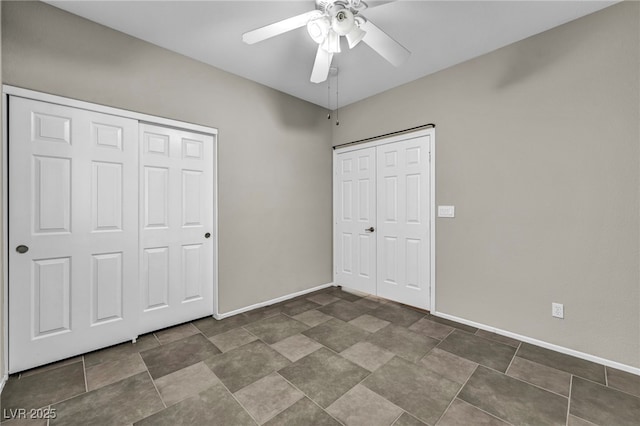 unfurnished bedroom featuring stone finish floor, a ceiling fan, and baseboards