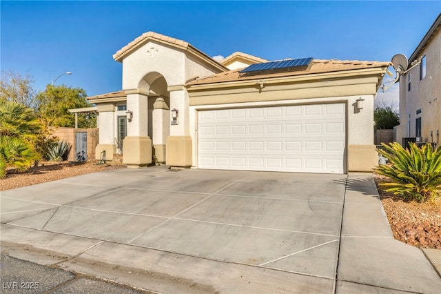 mediterranean / spanish home featuring a garage, solar panels, a tile roof, concrete driveway, and stucco siding