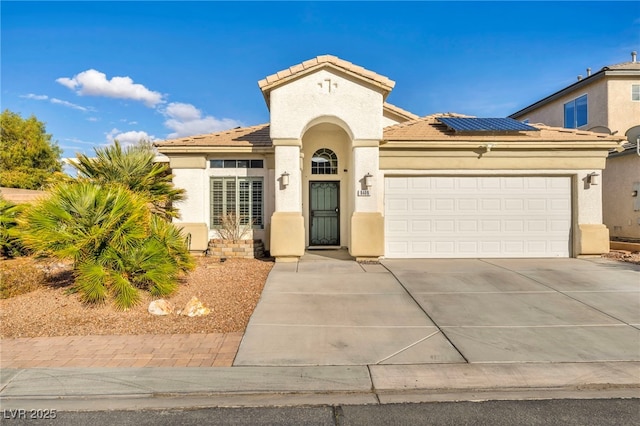 mediterranean / spanish home featuring driveway, solar panels, a tiled roof, an attached garage, and stucco siding