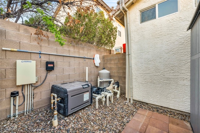 exterior details featuring pump, fence, and stucco siding