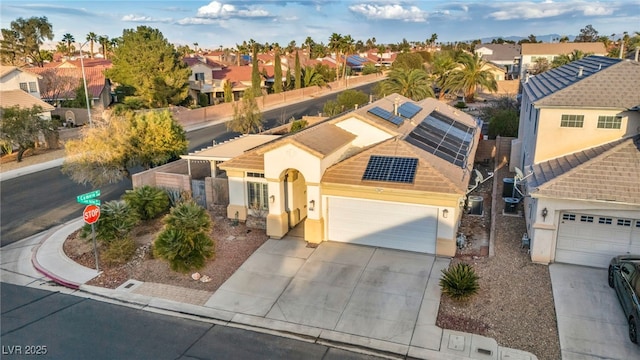 view of front of home featuring driveway, stucco siding, a residential view, and roof mounted solar panels