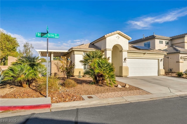 mediterranean / spanish-style home featuring a garage, a tile roof, concrete driveway, and stucco siding