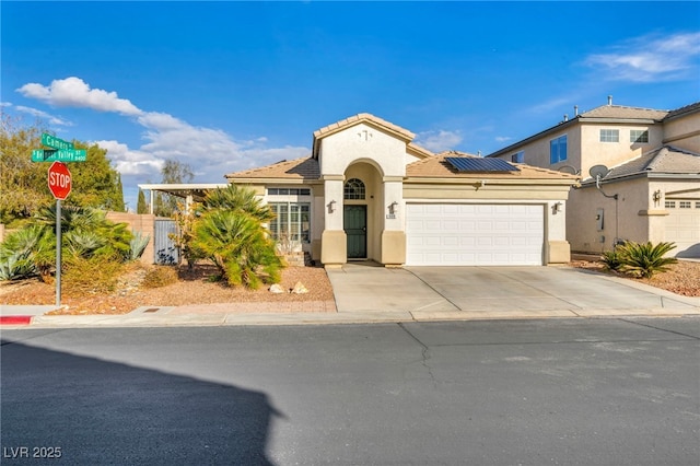 mediterranean / spanish-style home featuring a tile roof, stucco siding, solar panels, concrete driveway, and an attached garage