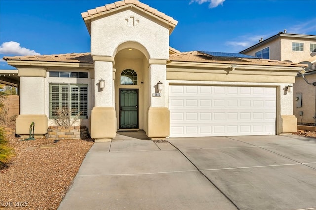 mediterranean / spanish-style house with concrete driveway, an attached garage, a tiled roof, and stucco siding