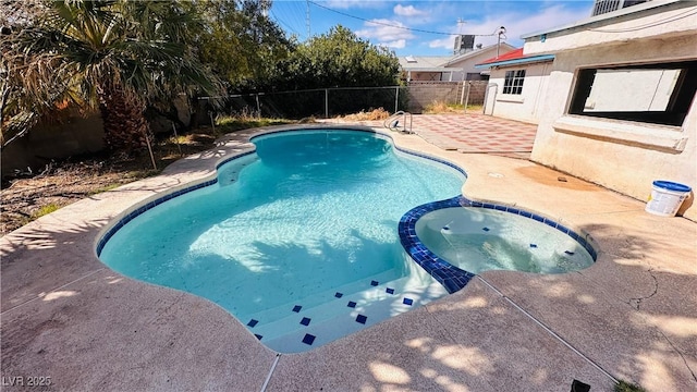 view of swimming pool with a pool with connected hot tub, a patio area, and a fenced backyard