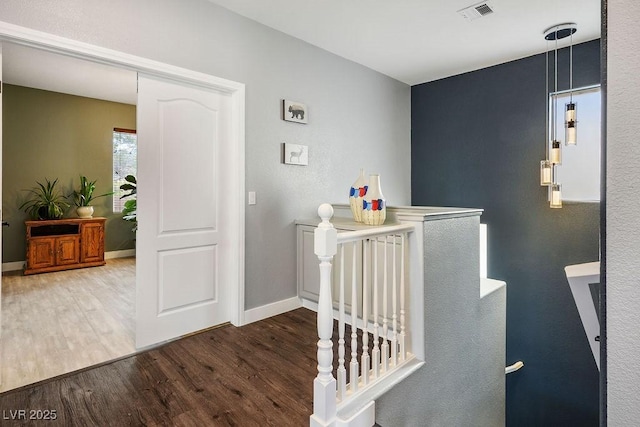 hallway featuring visible vents, baseboards, and wood finished floors