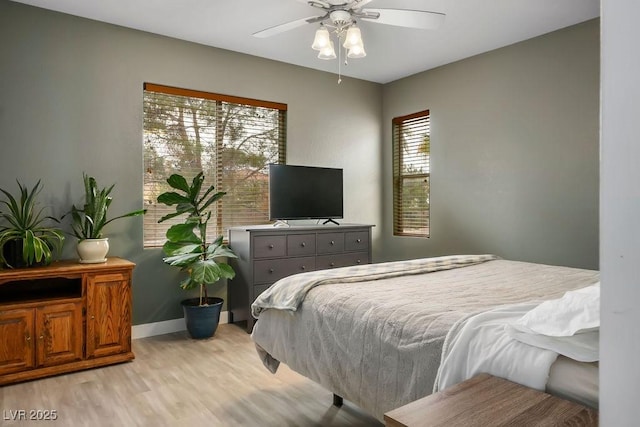 bedroom featuring baseboards, ceiling fan, and light wood finished floors