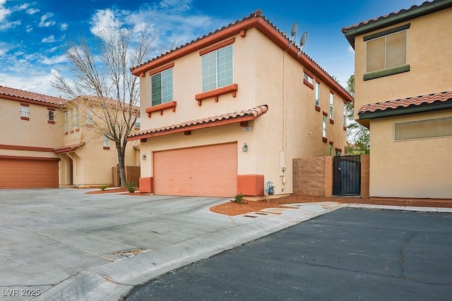 mediterranean / spanish-style house with stucco siding, a tile roof, a gate, concrete driveway, and a garage