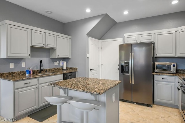 kitchen featuring dark stone counters, a center island, stainless steel fridge with ice dispenser, and a sink