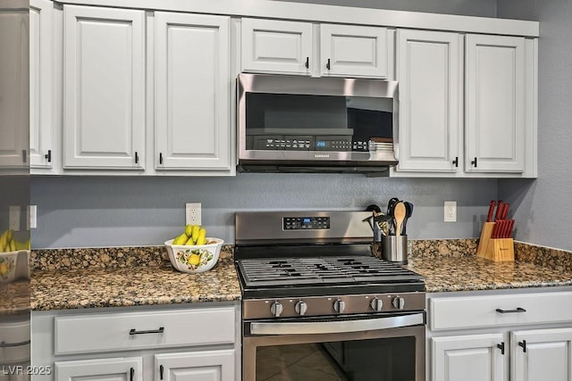 kitchen featuring dark stone countertops, white cabinets, and appliances with stainless steel finishes