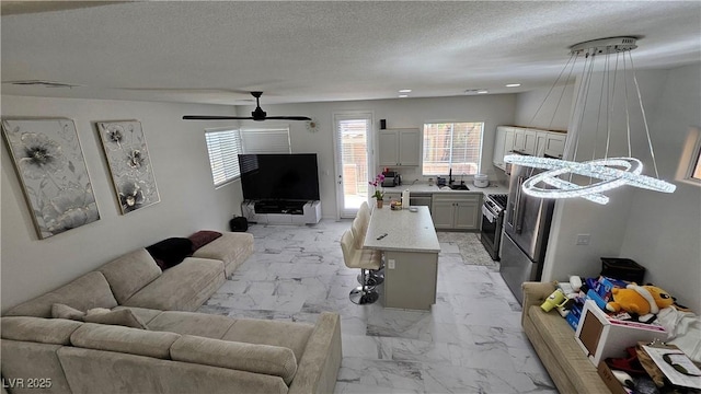 living room with a textured ceiling, marble finish floor, ceiling fan, and visible vents