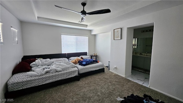 bedroom featuring connected bathroom, a ceiling fan, baseboards, a tray ceiling, and carpet