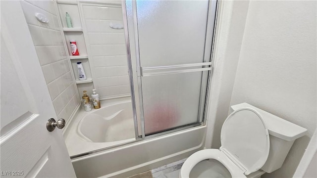 bathroom with toilet and bath / shower combo with glass door