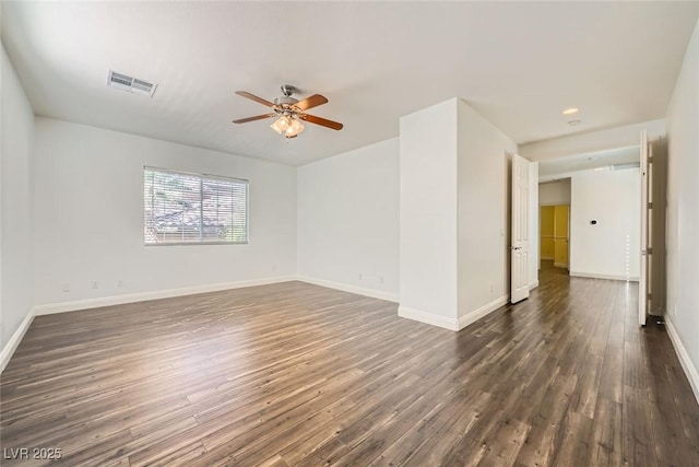 empty room with dark wood-style floors, a ceiling fan, visible vents, and baseboards