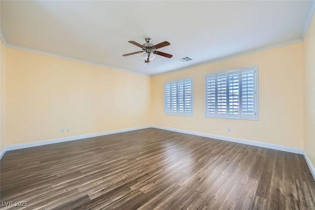 spare room featuring a ceiling fan, visible vents, baseboards, ornamental molding, and dark wood finished floors