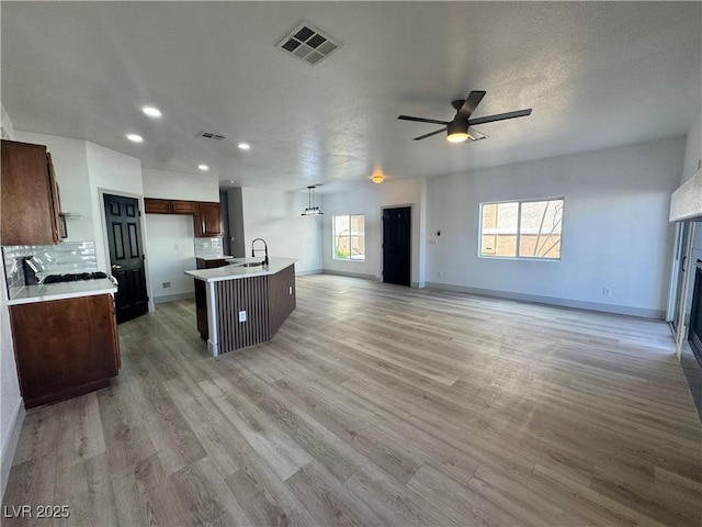 kitchen with open floor plan, visible vents, a sink, and light wood finished floors