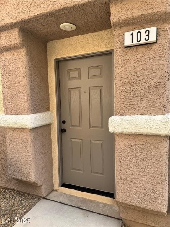 doorway to property featuring stucco siding