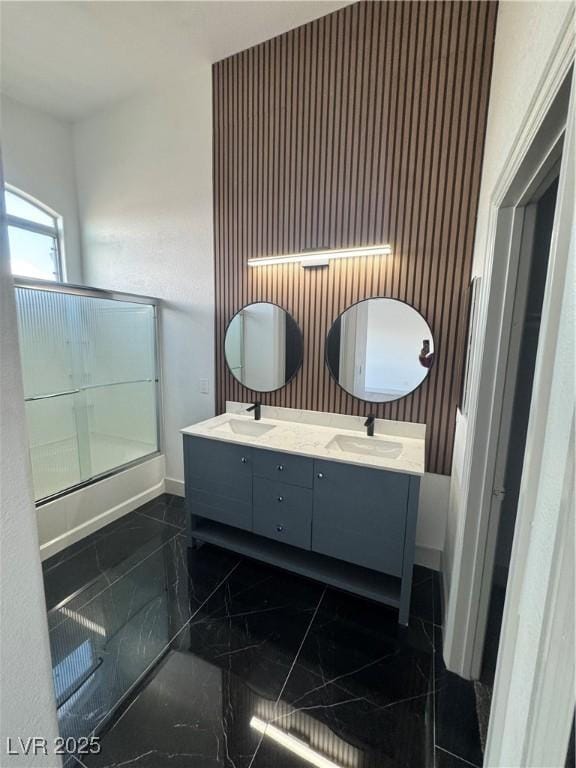 full bath with marble finish floor, double vanity, a sink, and baseboards