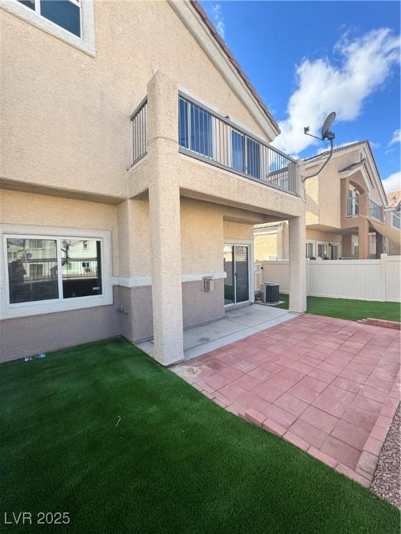 back of house with a balcony, fence, central air condition unit, a patio area, and stucco siding