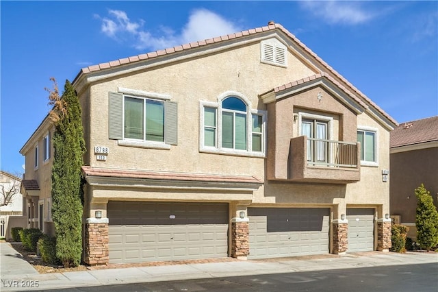 townhome / multi-family property with stone siding, stucco siding, a tile roof, and a garage