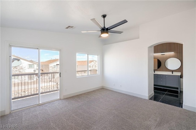 empty room with ceiling fan, dark colored carpet, baseboards, and visible vents