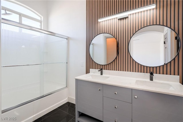 bathroom featuring a sink, baseboards, wallpapered walls, and enclosed tub / shower combo