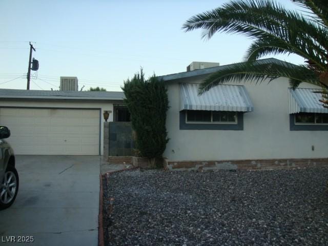 view of property exterior with a garage, driveway, and stucco siding