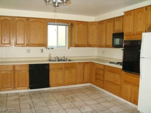 kitchen with black appliances, light countertops, a sink, and brown cabinetry