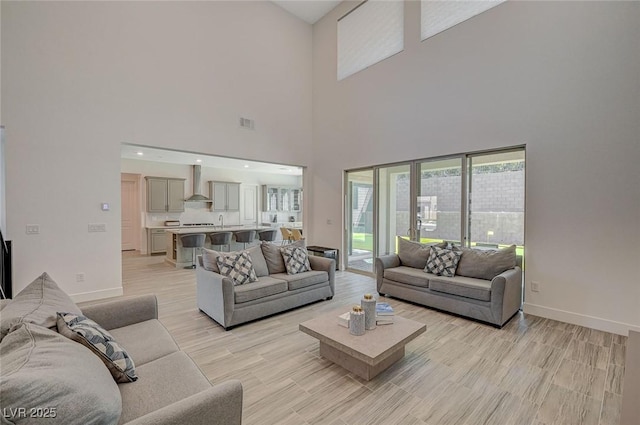 living room with light wood-style floors, visible vents, and baseboards