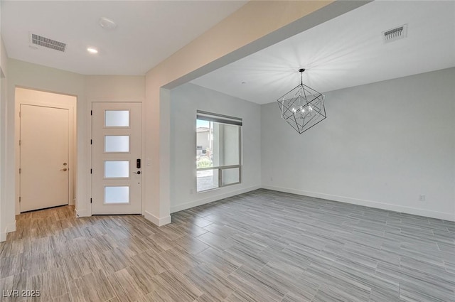 foyer featuring light wood finished floors, visible vents, and baseboards