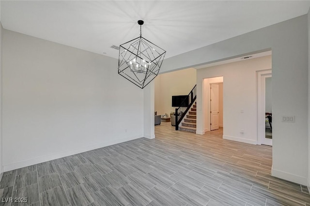 empty room featuring visible vents, stairway, baseboards, and wood finish floors