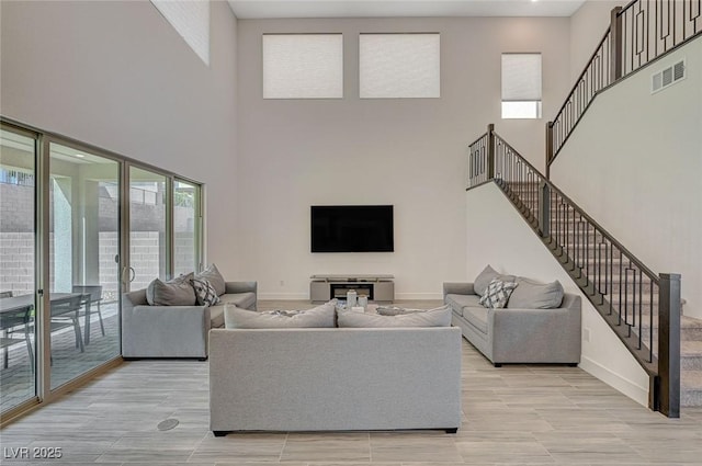 living area featuring stairway, baseboards, visible vents, and light wood-style flooring