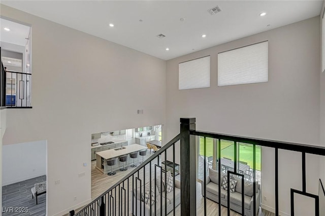 interior space with recessed lighting, visible vents, an upstairs landing, and wood finished floors