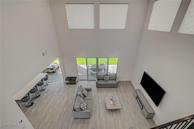 living room featuring visible vents, wood finished floors, a towering ceiling, and baseboards