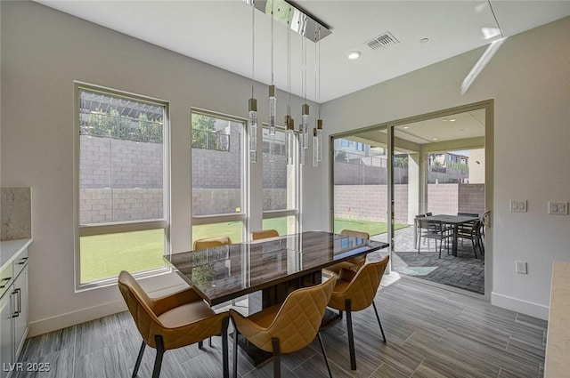 dining room featuring baseboards, wood finish floors, visible vents, and a healthy amount of sunlight